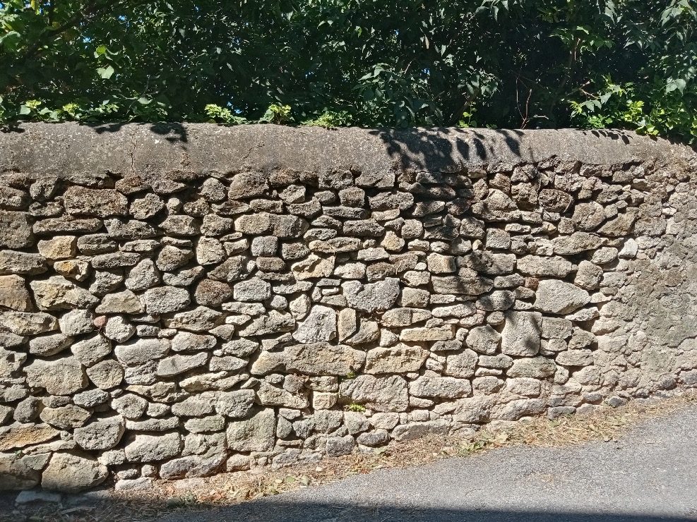 Mur en pierre sèche : des pierres plates de tailles inégales appareillées sans mortier, en assises régulières.